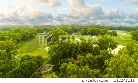 A panoramic aerial view of a golf course with lush greenery and dramatic cloudy skies 122248111