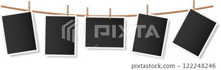 Five blank photographs or snapshots, softly shadowed, hang on a clothesline secured with wooden clothespins, creating a nostalgic display perfect for capturing cherished memories Five blank photographs or snapshots, softly shadowed, hang on a clothesline secured with wooden clothespins, creating a nostalgic display perfect for capturing cherished memories 122248246