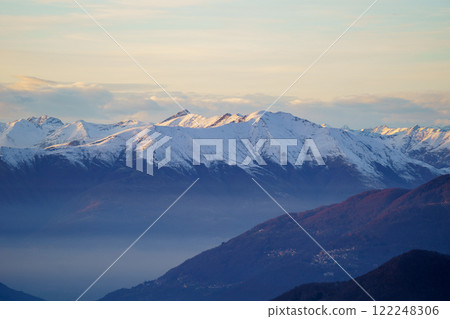Misty Mountain Valley with Snow-Capped Peaks at Dusk near Piani di Bobbio in Italy 122248306
