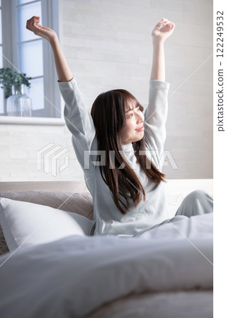 A woman stretching and waking up in bed 122249532