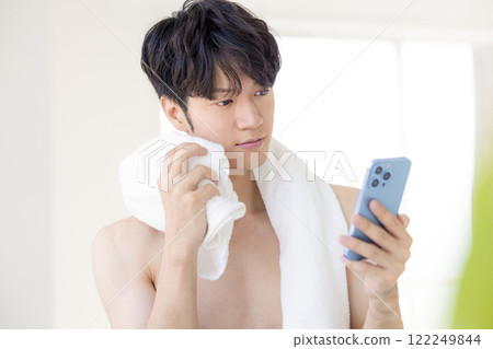 Beauty image: A man looking at his smartphone after taking a bath 122249844