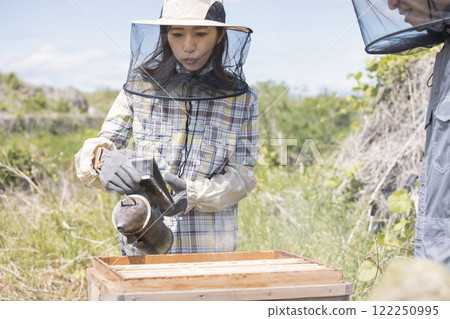 Beekeeping image: A woman using a smoker 122250995