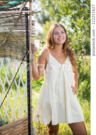 Female peasant girl stands near garden bed, near chicken coop and enjoys country activities Female peasant girl stands near garden bed, near chicken coop and enjoys country activities 122251627
