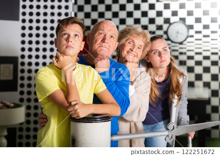 Pensive elderly grandparents together with their children solve a puzzle in quest room 122251672