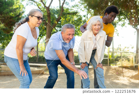 Happy casual diverse pensioners exercising together petanque in a sunny park in Spain 122251676