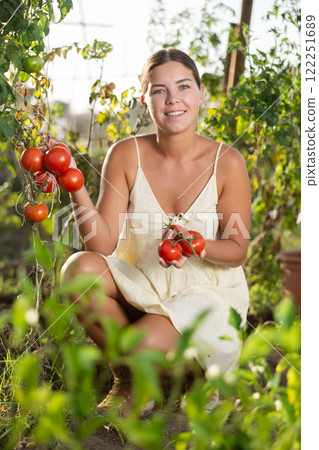 Smiling young girl posing with red tomatoes in garden 122251689