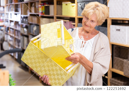 Mature woman choosing storage basket at shop Mature woman choosing storage basket at shop 122251692