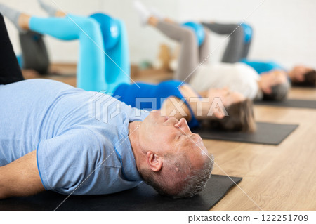 Elderly man training with bender ball at pilates workout 122251709