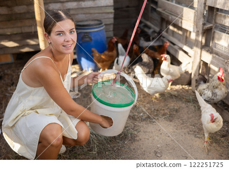 Young woman feeding chickens in henhouse 122251725