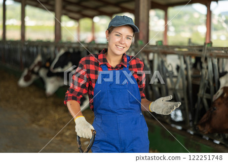 Portrait of successful girl farmer standing in open cowshed at dairy cow farm Portrait of successful girl farmer standing in open cowshed at dairy cow farm 122251748