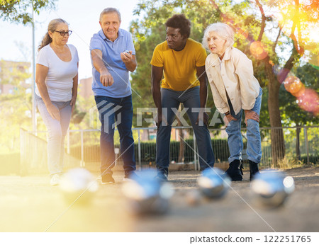 Company of friendly mature people playing petanque in park Company of friendly mature people playing petanque in park 122251765