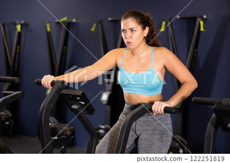 Girl are training on a spin bike simulator. Healthy lifestyle Girl are training on a spin bike simulator. Healthy lifestyle 122251819