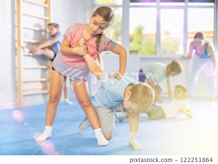 Kids in sportswear exercising self-protection techniques in pair during class Kids in sportswear exercising self-protection techniques in pair during class 122251864