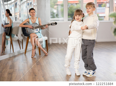 Boy and girl in pair train to dance tango during classes with accompaniment of guitar Boy and girl in pair train to dance tango during classes with accompaniment of guitar 122251884