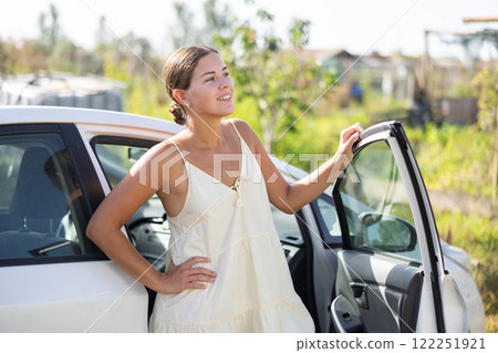 Young woman posing by car in garden 122251921