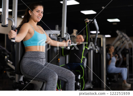 Sporty young woman using chest fly machine in gym Sporty young woman using chest fly machine in gym 122251939