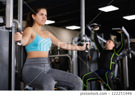 Active young woman training at chest fly machine in gym 122251946