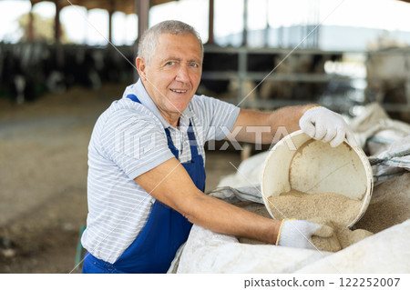 Elderly man scooping sand from bag 122252007