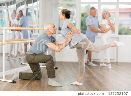 Mature man and woman practicing arabesque position of ballet in pair in dance studio Mature man and woman practicing arabesque position of ballet in pair in dance studio 122252107