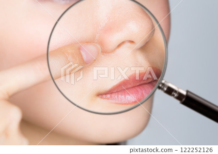 Magnifying a woman's nose with a loupe. Magnifying a woman's nose with a loupe. 122252126