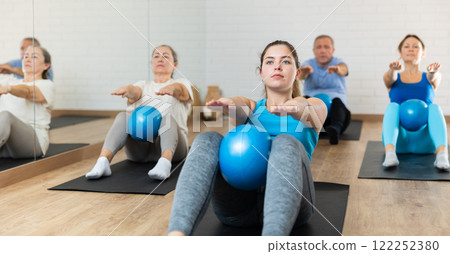 Young girl doing sit-ups with pilates ball in fitness center 122252380