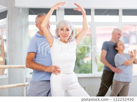 Mature woman practicing ballet positions in pair with man in dance studio 122252430