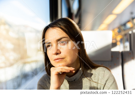 Contemplative woman looking out window while travelling by train 122252431