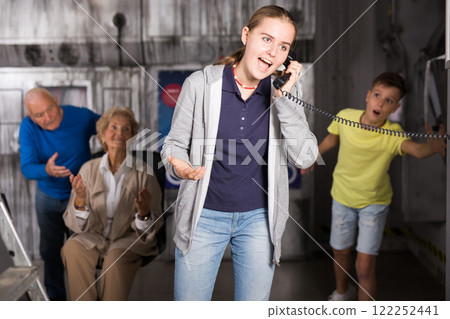 Scared girl shouts into telephone receiver Scared girl shouts into telephone receiver 122252441
