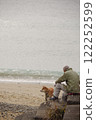下雪天，一位老人帶著他的狗在沙灘上散步 122252599
