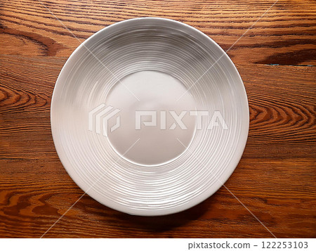 在一張棕色桌安置的一個白色盤 在一張棕色桌安置的一個白色盤 122253103