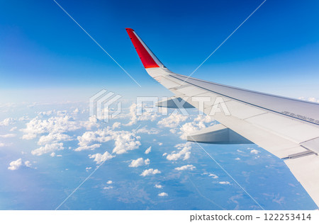 View from the airplane window at a beautiful cloudy sky and the airplane wing View from the airplane window at a beautiful cloudy sky and the airplane wing 122253414