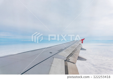 View from the airplane window at a beautiful cloudy sky and the airplane wing 122253418