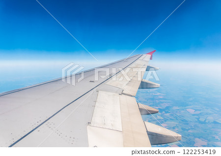 View from the airplane window at a beautiful cloudy sky and the airplane wing View from the airplane window at a beautiful cloudy sky and the airplane wing 122253419