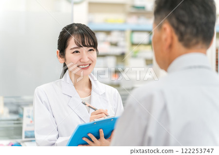 A female pharmacist counseling and interviewing a patient at the pharmacy counter A female pharmacist counseling and interviewing a patient at the pharmacy counter 122253747