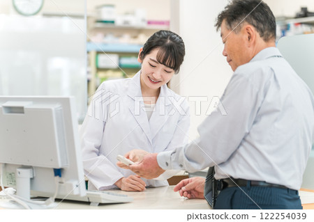 身為藥劑師/配藥員的女性在藥房向老年/中年男性解釋智能手機應用程序(用藥指導) 身為藥劑師/配藥員的女性在藥房向老年/中年男性解釋智能手機應用程序(用藥指導) 122254039