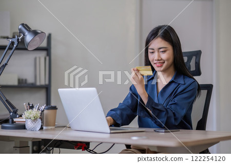 Young businesswoman makes online purchases on her laptop and pays with a credit card. Young businesswoman makes online purchases on her laptop and pays with a credit card. 122254120