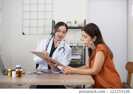 Female doctor and elderly female patient consulting about health problems in clinic 122254186