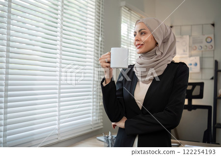 Confident Muslim businesswoman standing in front of desk in office 122254193