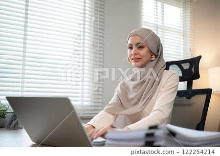 Muslim businesswoman working using laptop and taking notes on documents In the modern office Muslim businesswoman working using laptop and taking notes on documents In the modern office 122254214