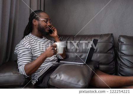 Young African American businessman spends his free time working from home on his laptop. Young African American businessman spends his free time working from home on his laptop. 122254221