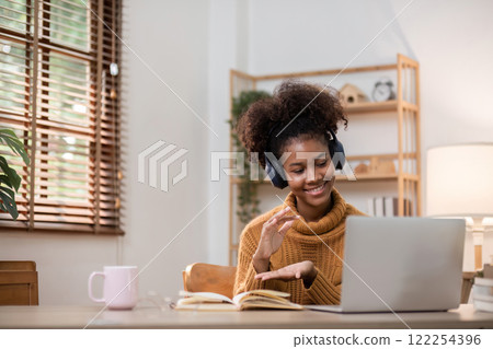 Young African Woman Relaxing at Home While Working Online with Laptop and Headphones in Cozy Living Room 122254396