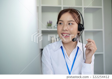 Call center agents wear headphones to talk to customers. Provide consultation via online channels on laptops Call center agents wear headphones to talk to customers. Provide consultation via online channels on laptops 122254412