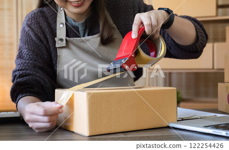 Young Asian female online business entrepreneur is preparing and packing products on the table to ship to customers. 122254426
