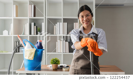 Young Asian housewife uses a vacuum cleaner to clean and vacuum the office. 122254437
