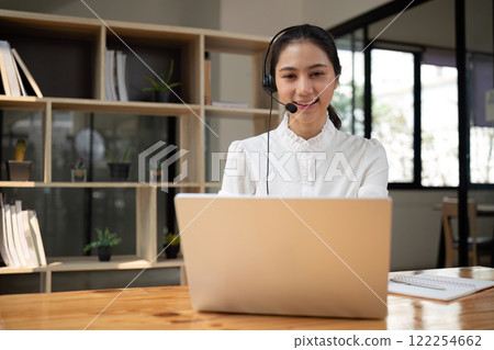 Call center agents wear headphones to talk to customers. Provide consultation via online channels on laptops 122254662