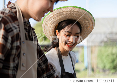 Cheerful Female Farmer Smiling in Sunlit Field Wearing Straw Hat and Apron, Embracing Sustainable Agriculture and Rural Lifestyle 122254711