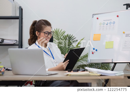 Beautiful determined business woman working using laptop recording data in modern office 122254775