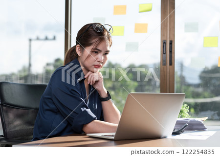 Tired businesswoman wearing glasses has a headache at work looking at a laptop computer in the office 122254835