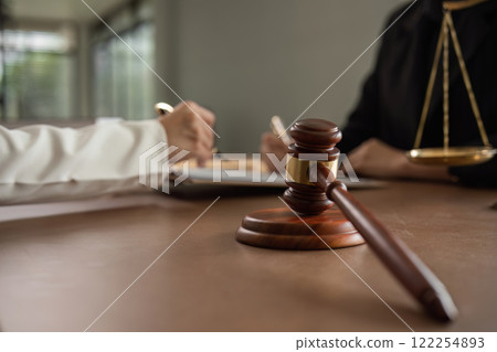 Lawyers and businesswomen join hands to reach an agreement on cooperation contract documents. In the lawyer's office There was a lawyer's hammer and scale on the table. 122254893