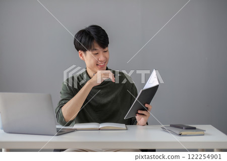 Portrait of a handsome young office worker intently studying how to do a presentation project on a laptop in his office. 122254901